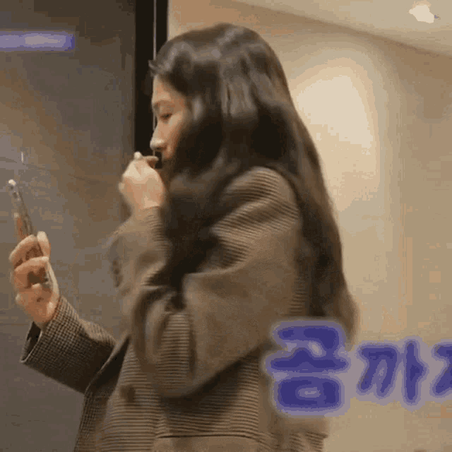 a woman in a plaid jacket is holding a cell phone in her hand ..