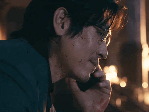 a man with blood on his face is talking on a phone