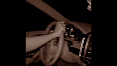 a person is holding a steering wheel in a car .