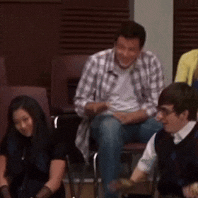 a group of people are sitting in chairs in a room and one of them is wearing a plaid shirt