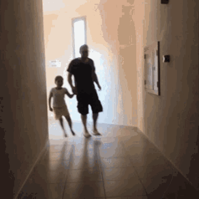 a man and a child are walking down a hallway .