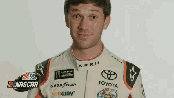 a man wearing a toyota racing suit is making a face .