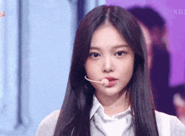 a close up of a woman wearing a microphone with kbs on the bottom right