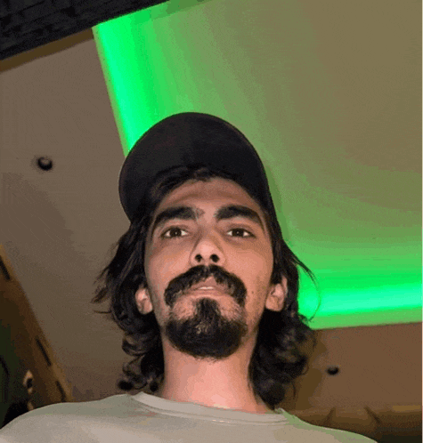 a man with long hair and a beard wearing a baseball cap
