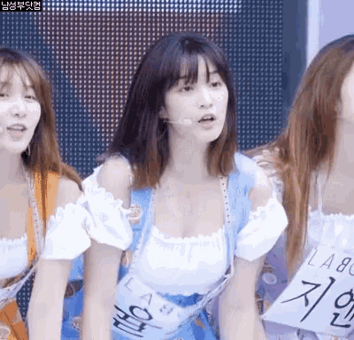 a group of women are standing next to each other and one of them has a sign that says ' a ' on it .