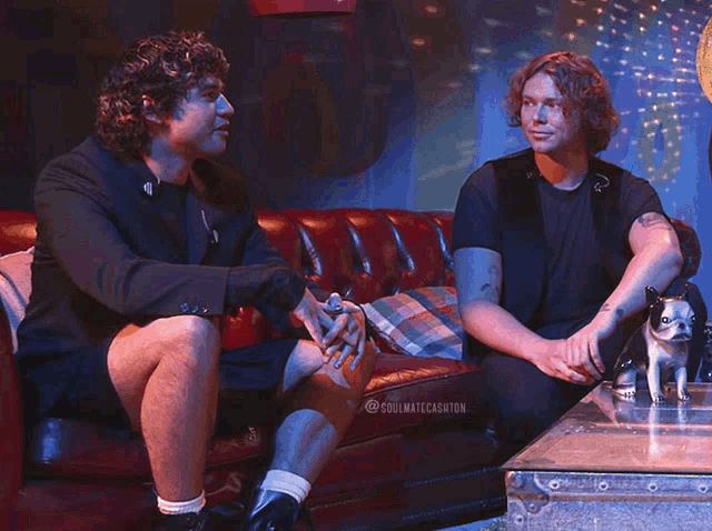 two men sitting on a couch with a small dog and the words soulmatecashton on the bottom right