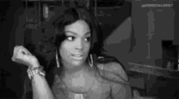 a black and white photo of a woman wearing earrings and a watch .
