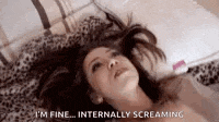 a woman is laying on a bed screaming and saying i 'm fine internally screaming .
