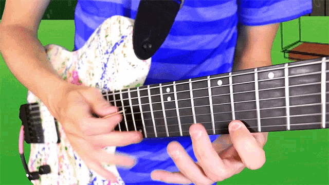 a man in a blue shirt is playing a white guitar