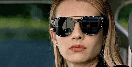a close up of a woman wearing sunglasses and making a face .