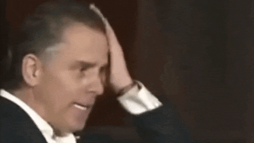 a man in a suit and tie is making a funny face and waving his hand .