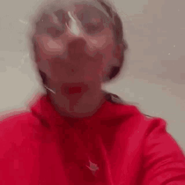 a woman in a red hoodie and sunglasses is taking a selfie with her face visible .