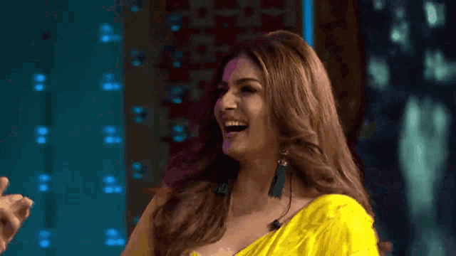 a woman in a yellow dress is laughing while standing next to a man .