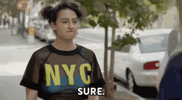 a woman wearing a nyc shirt is standing on a sidewalk next to a car .