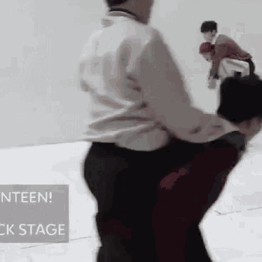 a man is carrying another man in his arms while another man watches .