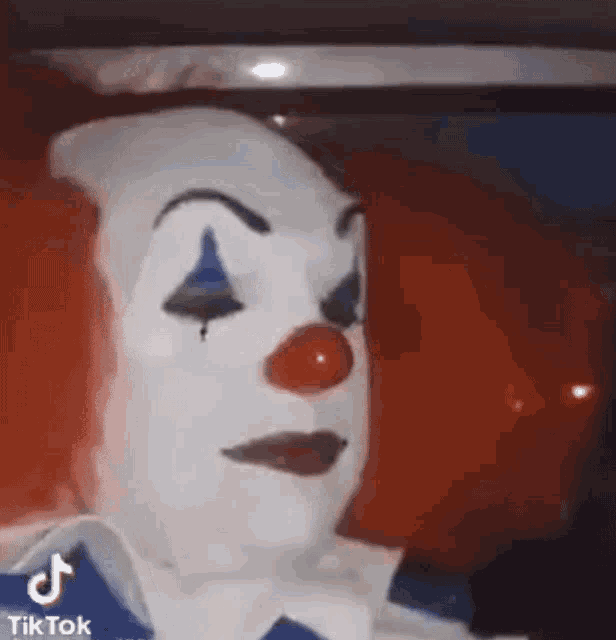 a close up of a clown with a red nose and white face paint .