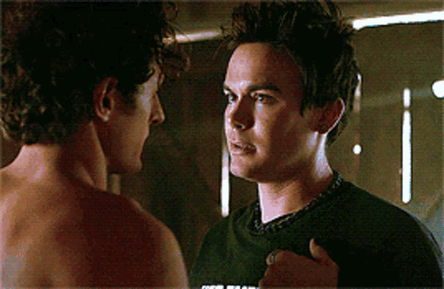 two shirtless men are looking at each other with one wearing a shirt that says " i love you " on it