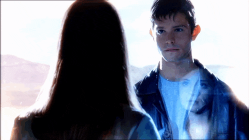 a man and a woman are looking at each other with a reflection of a woman in the man 's jacket