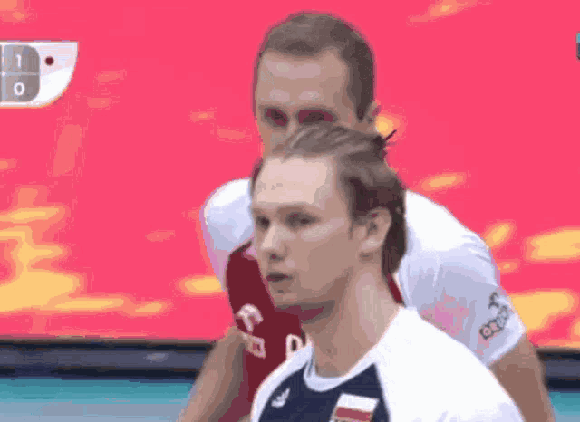 two men are playing volleyball and one of them has the letter a on his shirt