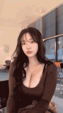 a woman with very large breasts is sitting in front of a large window .