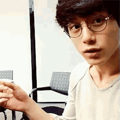 a young man wearing glasses is looking at the camera