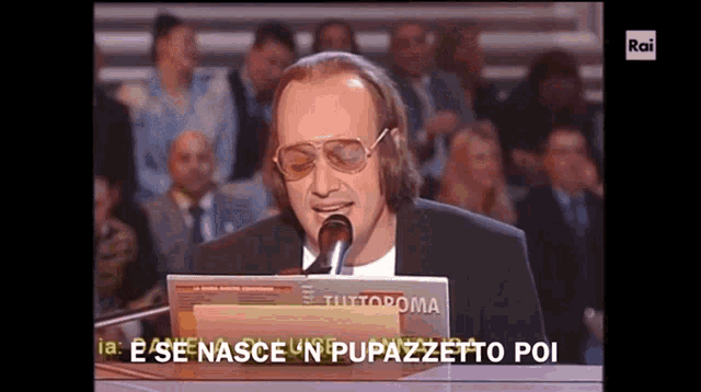 a man singing into a microphone with the words " e se nasce un pupazzetto poi " written below him
