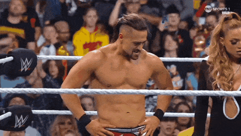 a man without a shirt is standing in a wrestling ring .