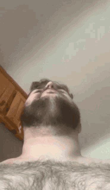 a man with a beard is looking up at the camera with his eyes closed