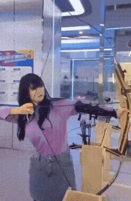 a woman is holding a bow and arrow in a room