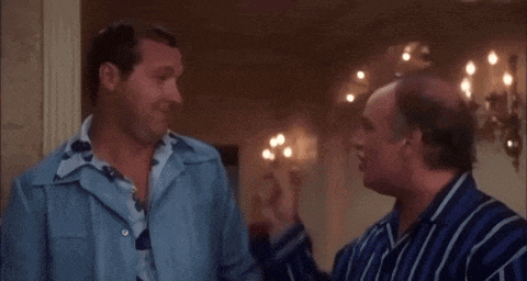 two men are standing next to each other and one of them is pointing at the other 's shirt .