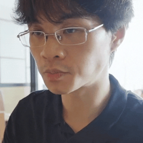 a man wearing glasses and a black shirt looks to the side