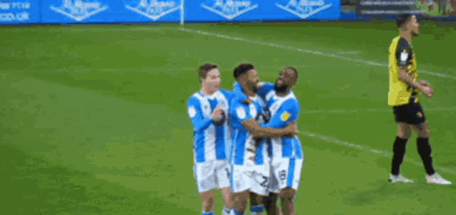 a group of soccer players wearing blue and white striped uniforms are celebrating a goal on a field .