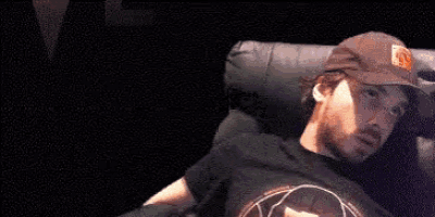 a man in a hat is laying on a couch with his arm outstretched
