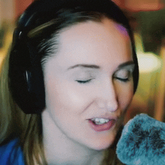 a close up of a woman wearing headphones and singing into a microphone
