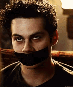 a close up of a man with a black tape around his mouth .