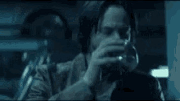 a man is drinking a glass of wine in a dark room .