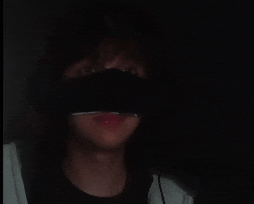 a close up of a person wearing a black mask in the dark .