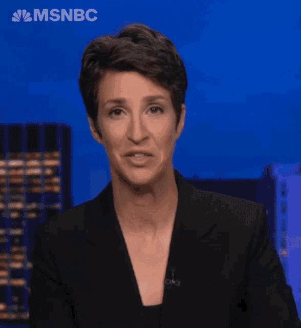 a woman is making a face in front of a sign that says msnbc on it