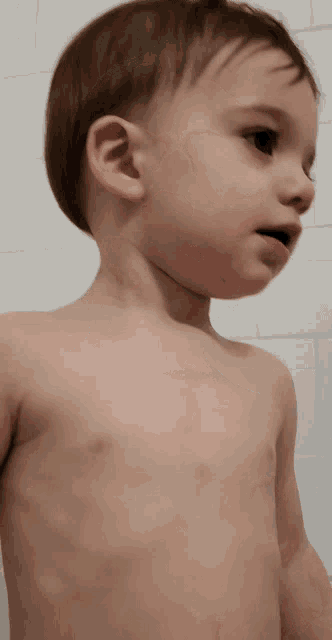 a little boy without a shirt is looking to the side