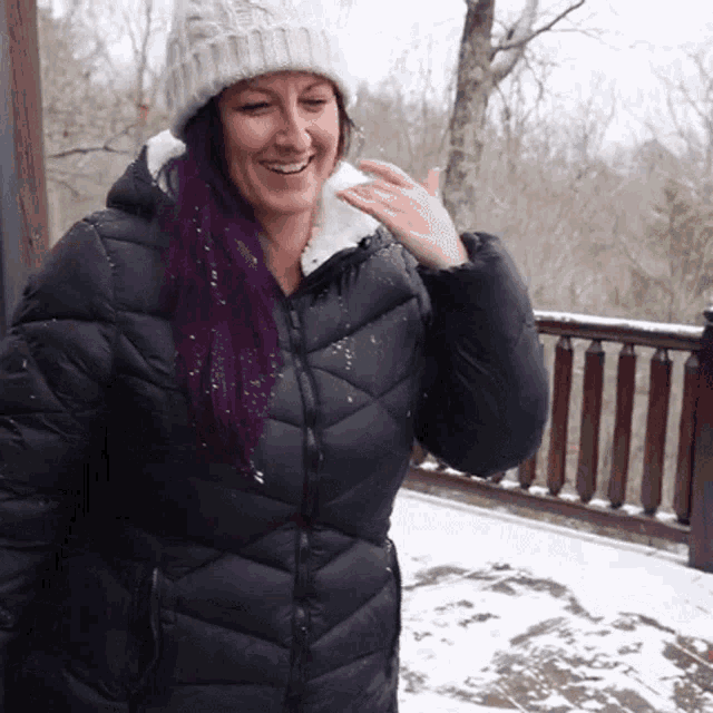 a woman with purple hair is wearing a black coat and a white hat
