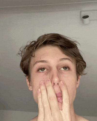 a young man covers his mouth with his hands