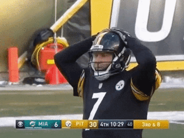 a football player wearing a number 7 jersey holds his helmet over his head