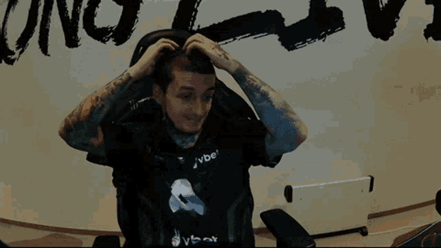 a man sitting in a chair with his arms outstretched wearing a shirt that says vbet