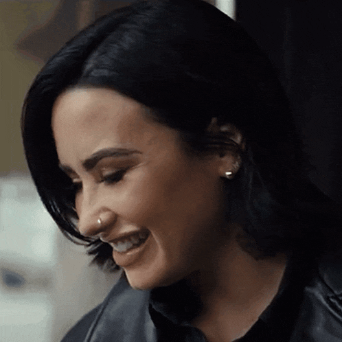 a woman with a nose ring is smiling and wearing a black jacket .