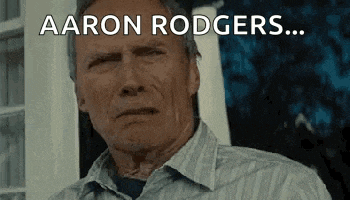 a man in a striped shirt is standing in front of a window with the words `` aaron rodgers '' written below him .