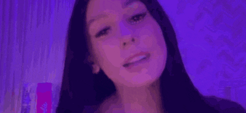 a close up of a woman 's face in front of a purple background .