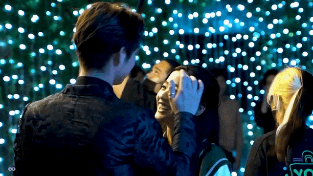 a man is touching a woman 's forehead in front of a display of blue lights