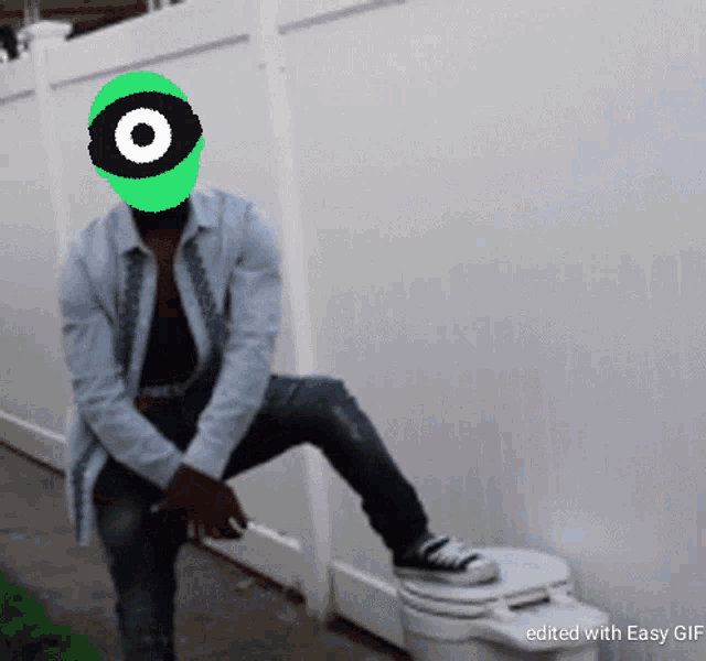 a man sitting on a toilet with a green eye on his face