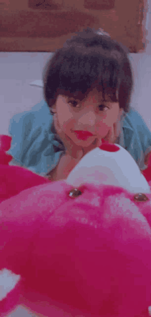 a little girl is laying on the floor with a pink stuffed animal