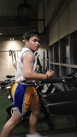 a man running on a treadmill in a gym wearing shorts that say lakers